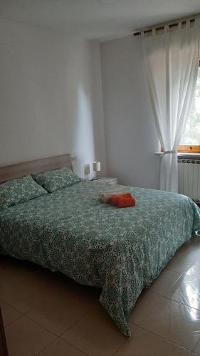 een slaapkamer met een bed met een groen dekbed en een raam bij La casa sul lago dorato in Magione
