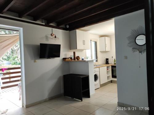 eine Küche mit weißen Schränken und einem TV an der Wand in der Unterkunft Ô Chalet in Saint-Philippe