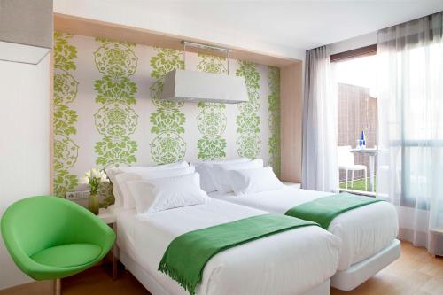 - une chambre avec un lit et une chaise verte dans l'établissement NH Madrid Principe de Vergara, à Madrid