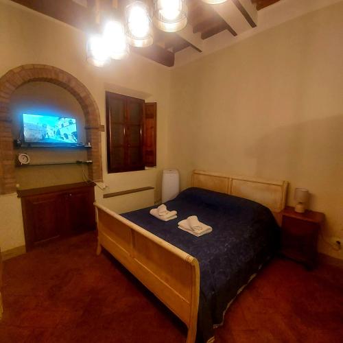 a bedroom with a bed and a flat screen tv at QUERCECCHIO Relax in San Gimignano