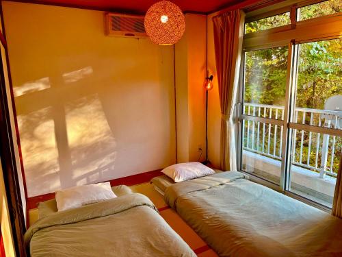 two beds sitting in a room with a window at FUJI Forest House103 in Gotemba