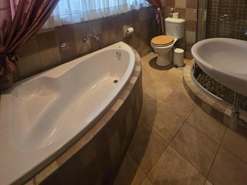 a bathroom with a tub and a toilet and a sink at Swasti Guesthouse in Boksburg