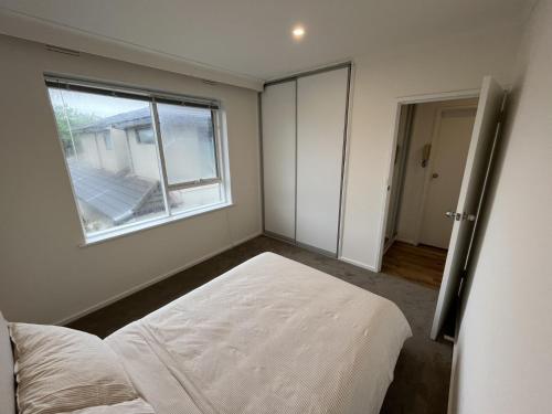 an empty bedroom with a bed and a window at Private Cozy Room in a Spacious Flat in Carnegie in Carnegie
