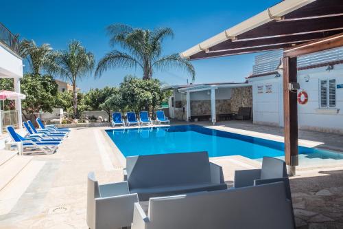 a swimming pool with blue lounge chairs and palm trees at Papas Family Villa in Paralimni