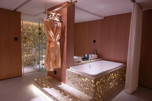 ein Badezimmer mit Badewanne und Dusche mit Beleuchtung in der Unterkunft Shuitiao Boli Hotel (Yangshuo Shili Gallery Yulonghe Branch) in Gaotian