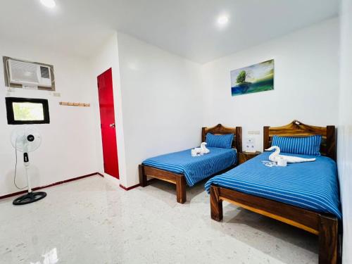 Una habitación con dos camas y un ventilador. en Panda Guest House, en Corón