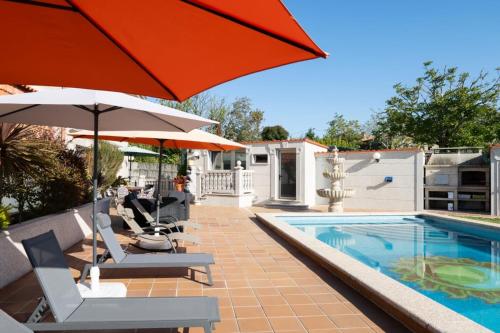 a pool with umbrellas and chairs next to a swimming pool at Abetos Panxon in Nigrán