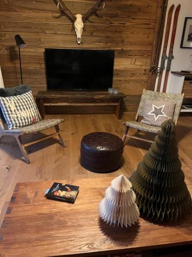 a living room with a television and a table with a table sidx sidx at Stube9 am Feldberg, direkt an der Skipiste, Ski in-Ski out in Feldberg