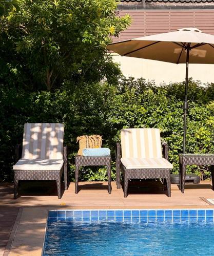 two chairs and an umbrella next to a swimming pool at Miloft Suvarnabhumi Airport Hotel in Lat Krabang