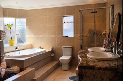 a bathroom with a tub and a toilet and a sink at The Condor Nest! in Sandton