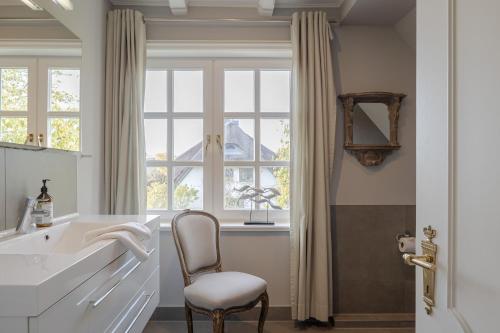 a bathroom with a chair and a sink and a window at Leo in Keitum
