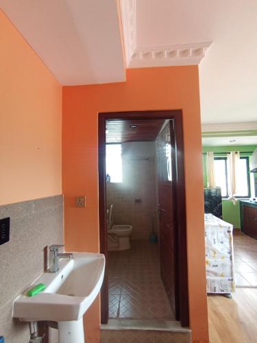 baño de color naranja con lavabo y aseo en Maskey Niwas, en Katmandú