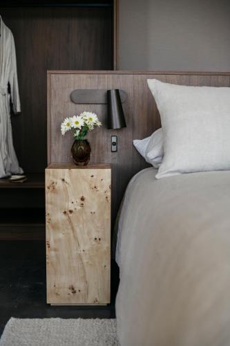 a vase of flowers on a wooden table next to a bed at Box Hill Esperance in Esperance