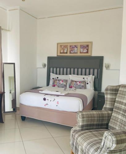 une chambre avec un grand lit et une chaise dans l'établissement Real Favour Suites Guest House, à Palatswe