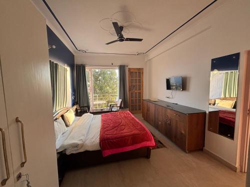 Un dormitorio con una cama y un ventilador de techo. en Hotel Goludev Valley View, en Nainital