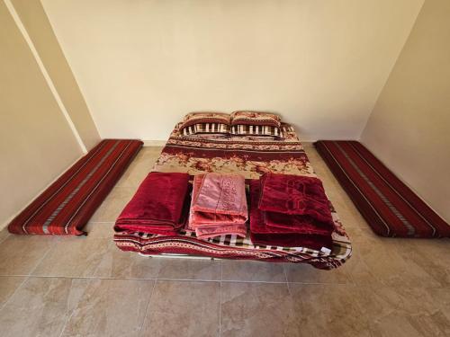 małe łóżko w pokoju z czerwonymi kocami w obiekcie Rum Adventures Hostel w mieście Wadi Rum