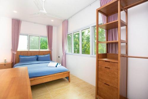 Japanese houses in Phuket في Ban Thalat Choeng Thale: غرفة نوم بها سرير ورف كتب