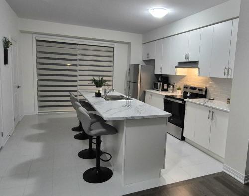 a kitchen with white cabinets and a counter with stools at First Class Ensuite Room in Brantford