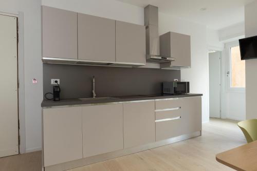 Una cocina con gabinetes blancos y un fregadero. en EUR Suites, en Roma