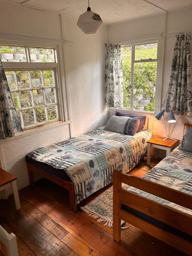 a bedroom with two beds and two windows at Explore River Cottage Ocean View in Seafield
