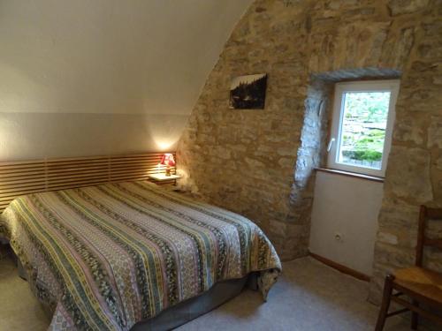 Un dormitorio con una cama en una pared de piedra. en La Maison du Berger, en La Cresse