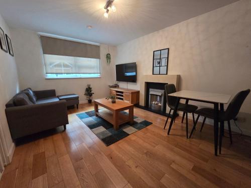 a living room with a couch and a table and a television at Central Two Bedroom Apartment Near Union Square -Free Parking in Aberdeen