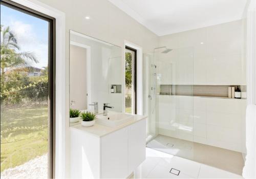 a white bathroom with a sink and a mirror at Creekside Manor - Spacious | Nature & Serenity - Holiday Home in Gold Coast