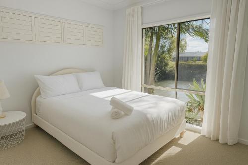 a white bedroom with a bed and a large window at Creekside Manor - Spacious | Nature & Serenity - Holiday Home in Gold Coast