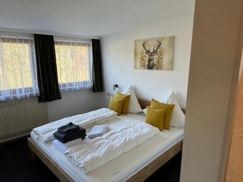 a bedroom with a bed with white sheets and yellow pillows at Haus Anna in Alpirsbach