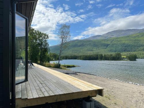 a wooden deck next to a body of water at Cabin By Rossfjordvannet In Arctic Scenery 