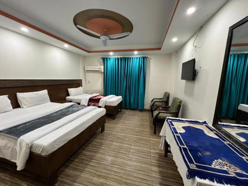 a hotel room with two beds and a chair at Hotel The Queen in Rawalpindi
