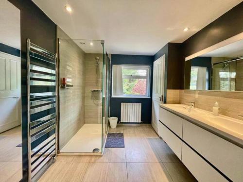 ein Badezimmer mit Dusche und zwei Waschbecken und einer Glasduschkabine in der Unterkunft Family-Game room-Sleeps 10-Parking-Pets-Bbq in Harlow