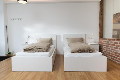 two white beds in a room with a brick wall at Kara Ben Nemsi in Ilmmünster