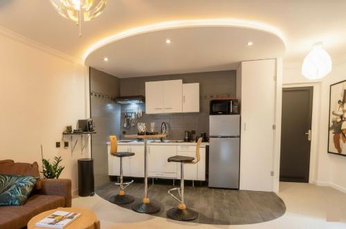 a kitchen and living room with a couch and a table at Appart'Hotel Premium Le Roitelet - Parking Privé & Entrée Autonome in Tullins