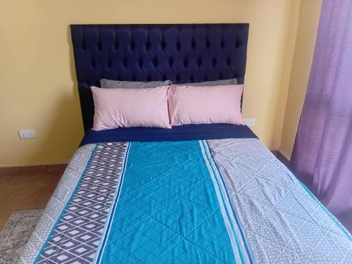 un letto con testiera nera e cuscini rosa di ThandyTasha luxury apartments a Lusaka