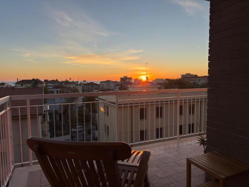 a balcony with a chair and a sunset on a building at Terrazza vista mare-Parcheggio gratuito -3Min A14 -Mastrangelo Beach in Grottammare