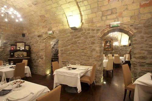 a restaurant with white tables and chairs and a stone wall at Hotel Rural Bidean in Puente la Reina