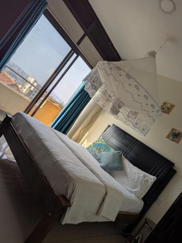 a bed in a room with a large window at Kampala suites Kisementi in Kampala