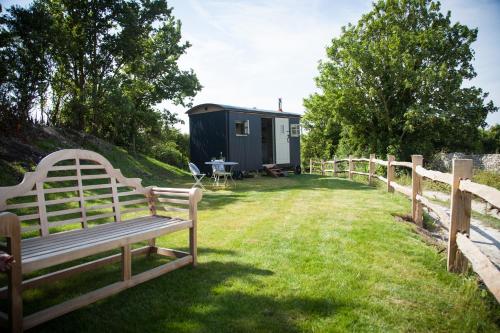 a bench sitting in the grass in front of a tiny house at Cobbe Place Farm Shepherds Hut in Beddingham