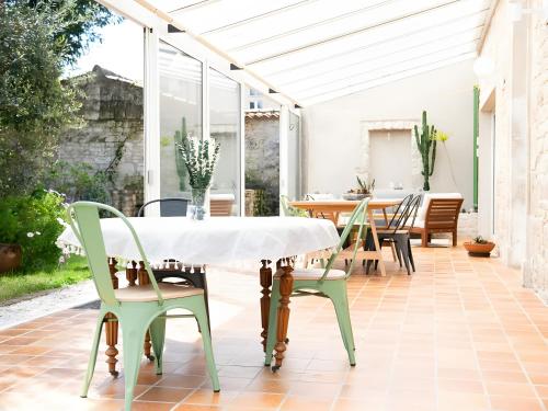 einen Wintergarten mit einem Tisch und Stühlen auf einer Terrasse in der Unterkunft La Maison De Famille in Luçon