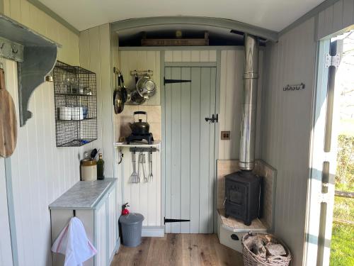 a kitchen with a stove in the corner of a room at Cobbe Place Farm Shepherds Hut in Beddingham