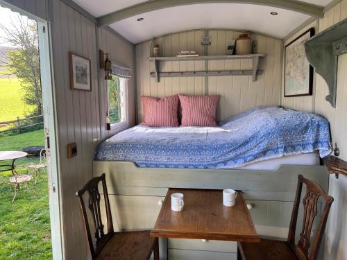 a bed in a small room with a table and chairs at Cobbe Place Farm Shepherds Hut in Beddingham