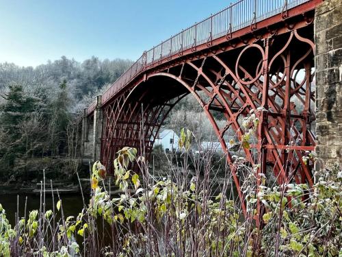eine rote Brücke mit einem Zug darauf in der Unterkunft 2 The Grove in Coalbrookdale