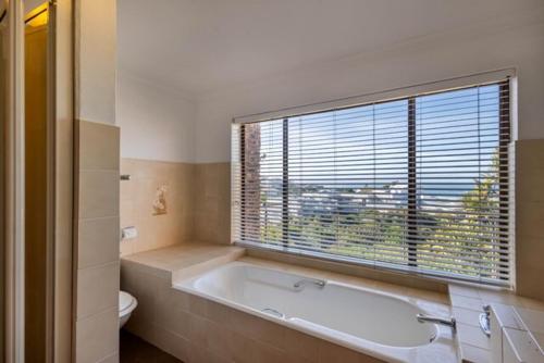 een badkamer met een bad, een toilet en een raam bij 8 Tarbet Ness in Vosburg