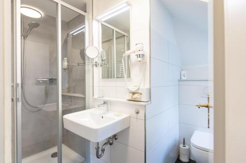 ein weißes Badezimmer mit Waschbecken und Dusche in der Unterkunft Hotel-Garni Haus Johanna in Einbeck