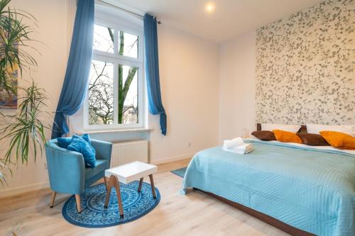 ein Schlafzimmer mit einem blauen Bett und einem blauen Stuhl in der Unterkunft Mysłowice Urban Harmony Apartment by BookingHost in Mysłowice