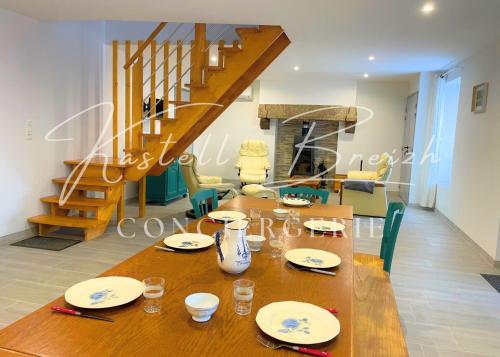 ein Holztisch mit Tellern darauf in einem Wohnzimmer in der Unterkunft Chez Jeanne, maison en pierre de pays avec jardin in Plougonver