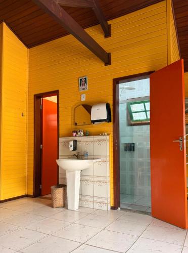 a bathroom with a sink and a yellow wall at Casinha Encantada-Café Cacupé Hospedagem in Florianópolis
