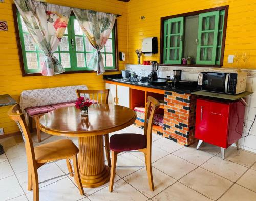 a kitchen with a table and chairs and a microwave at Complexo de Hospedagem e Gastronomia Café Cacupé in Florianópolis