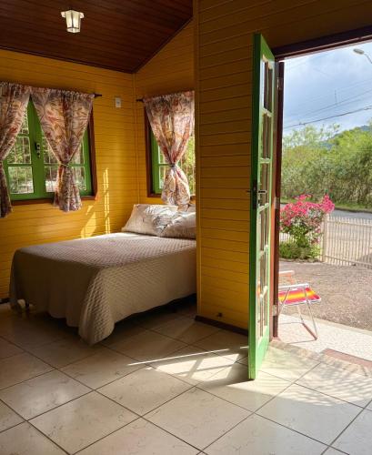 a bedroom with a bed and a open door at Casinha Encantada-Café Cacupé Hospedagem in Florianópolis
